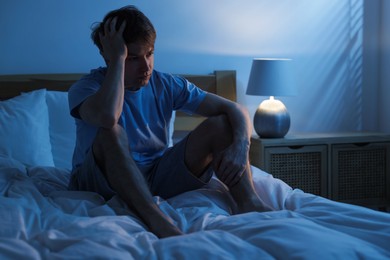 Photo of Frustrated man suffering from insomnia on bed indoors