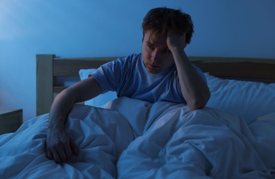 Photo of Frustrated man suffering from insomnia in bed indoors