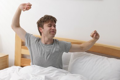 Photo of Man stretching in bed indoors. Good morning