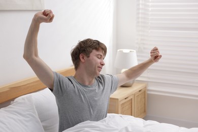 Photo of Man stretching in bed indoors. Good morning