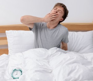 Photo of Man yawning in bed indoors. Good morning