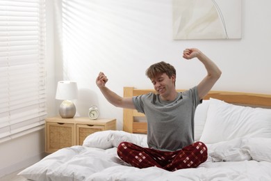 Photo of Happy man stretching on bed indoors. Good morning
