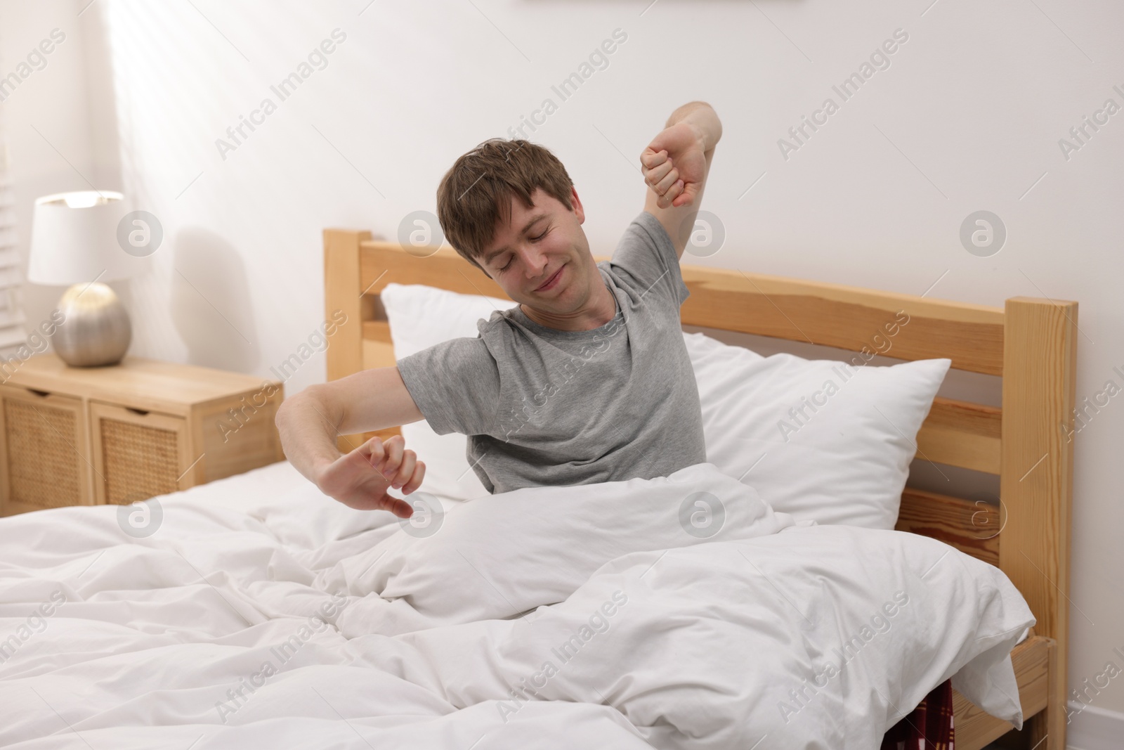 Man stretching in bed indoors. Good morning Photo of Man stretching in bed indoors. Good morning