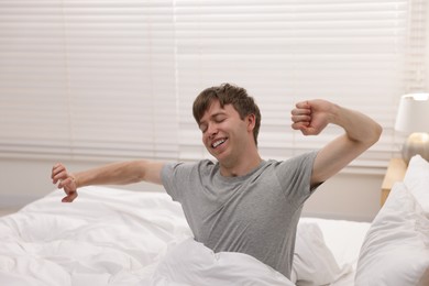 Photo of Happy man stretching in bed indoors. Good morning