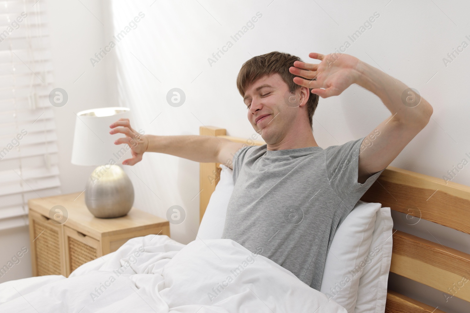 Man stretching in bed indoors. Good morning Photo of Man stretching in bed indoors. Good morning