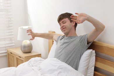 Photo of Man stretching in bed indoors. Good morning