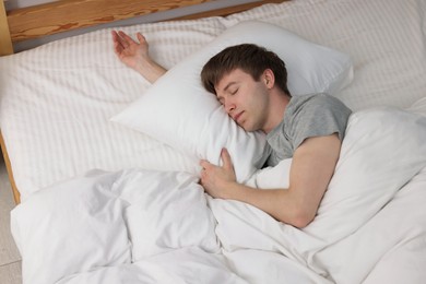 Photo of Young man sleeping in bed at home, above view