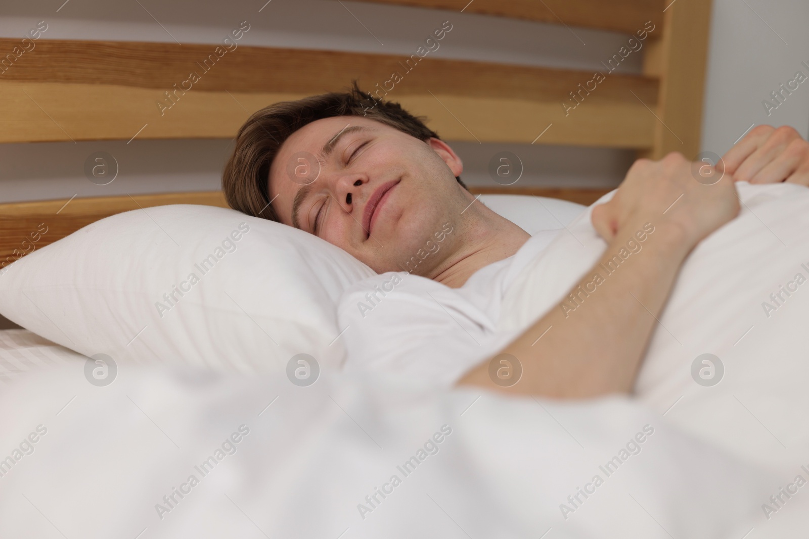 Young man sleeping in bed at home Photo of Young man sleeping in bed at home