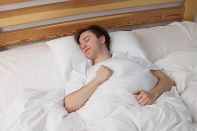 Photo of Young man sleeping in bed at home, above view