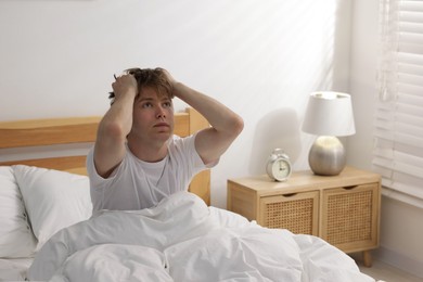 Photo of Tired man suffering from insomnia in bed indoors