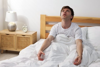 Photo of Tired man suffering from insomnia in bed indoors