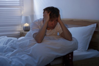 Photo of Frustrated man suffering from insomnia on bed indoors