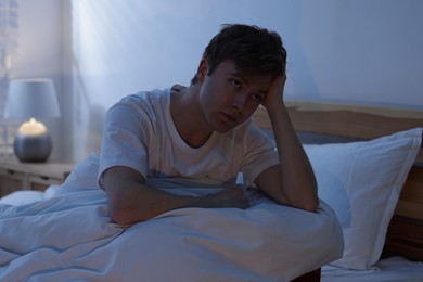 Photo of Frustrated man suffering from insomnia on bed indoors