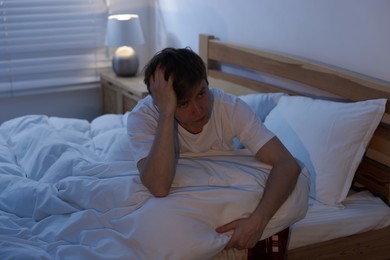 Photo of Frustrated man suffering from insomnia on bed indoors