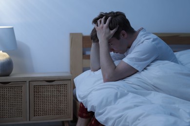 Photo of Frustrated man suffering from insomnia on bed indoors