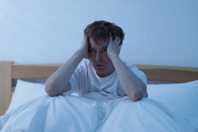 Photo of Frustrated man suffering from insomnia on bed indoors