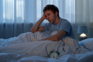 Photo of Frustrated man suffering from insomnia on bed indoors