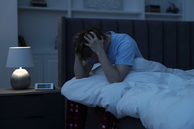 Photo of Frustrated man suffering from insomnia on bed indoors