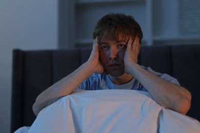 Photo of Frustrated man suffering from insomnia on bed indoors