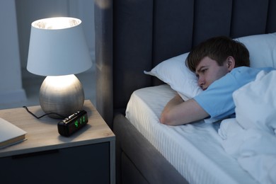 Photo of Frustrated man suffering from insomnia on bed indoors