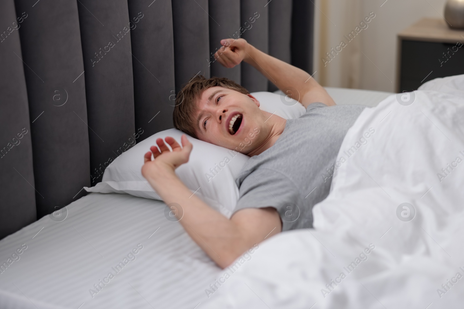 Man stretching in bed indoors. Good morning Photo of Man stretching in bed indoors. Good morning