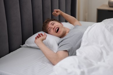 Photo of Man stretching in bed indoors. Good morning