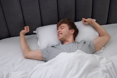 Photo of Happy man stretching in bed, above view