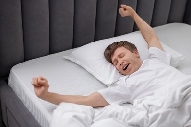 Photo of Man stretching in bed indoors. Good morning