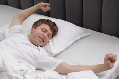 Photo of Happy man stretching in bed indoors. Good morning