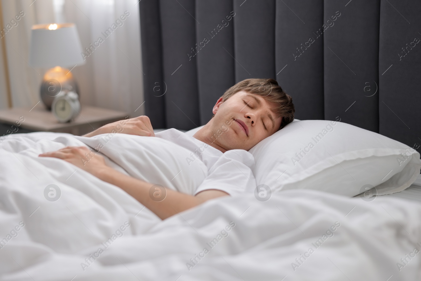 Young man sleeping in bed at home Photo of Young man sleeping in bed at home