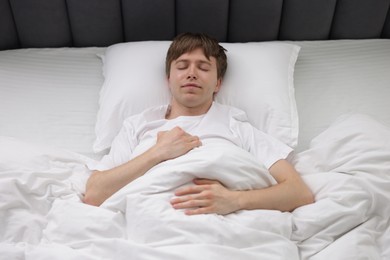 Photo of Young man sleeping in bed at home, above view
