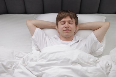 Photo of Young man sleeping in bed at home, top view