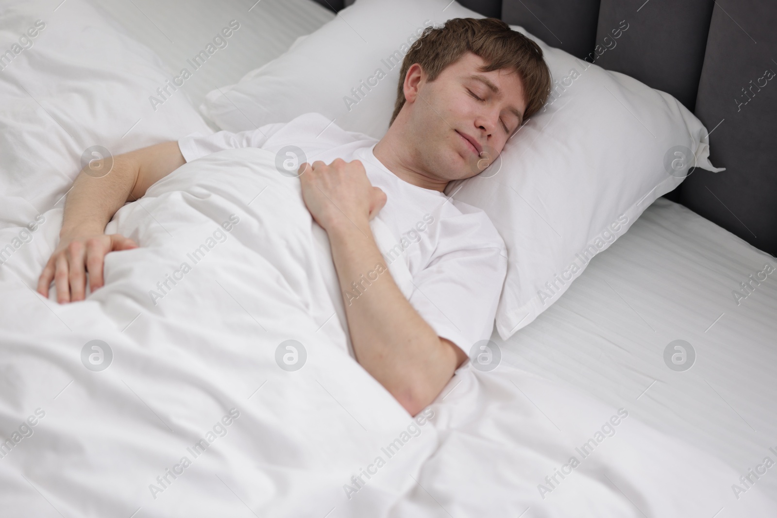Young man sleeping in bed at home Photo of Young man sleeping in bed at home