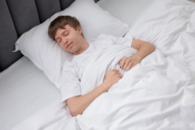 Photo of Young man sleeping in bed at home, above view