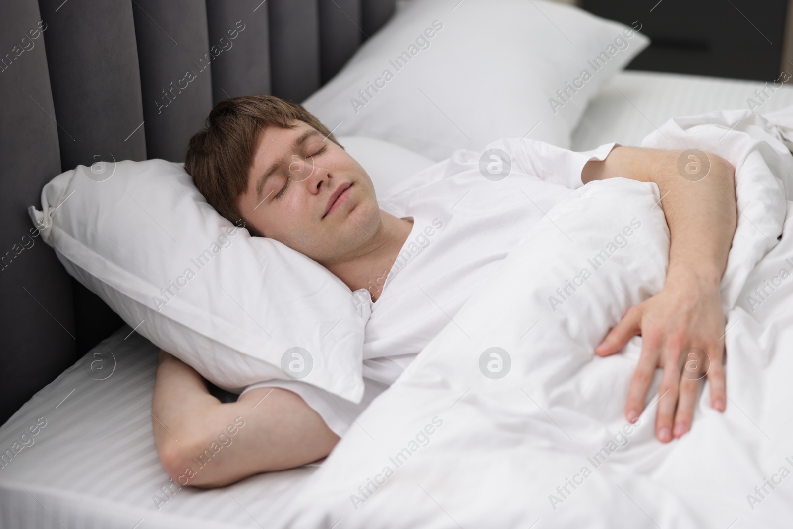 Young man sleeping in bed at home Photo of Young man sleeping in bed at home