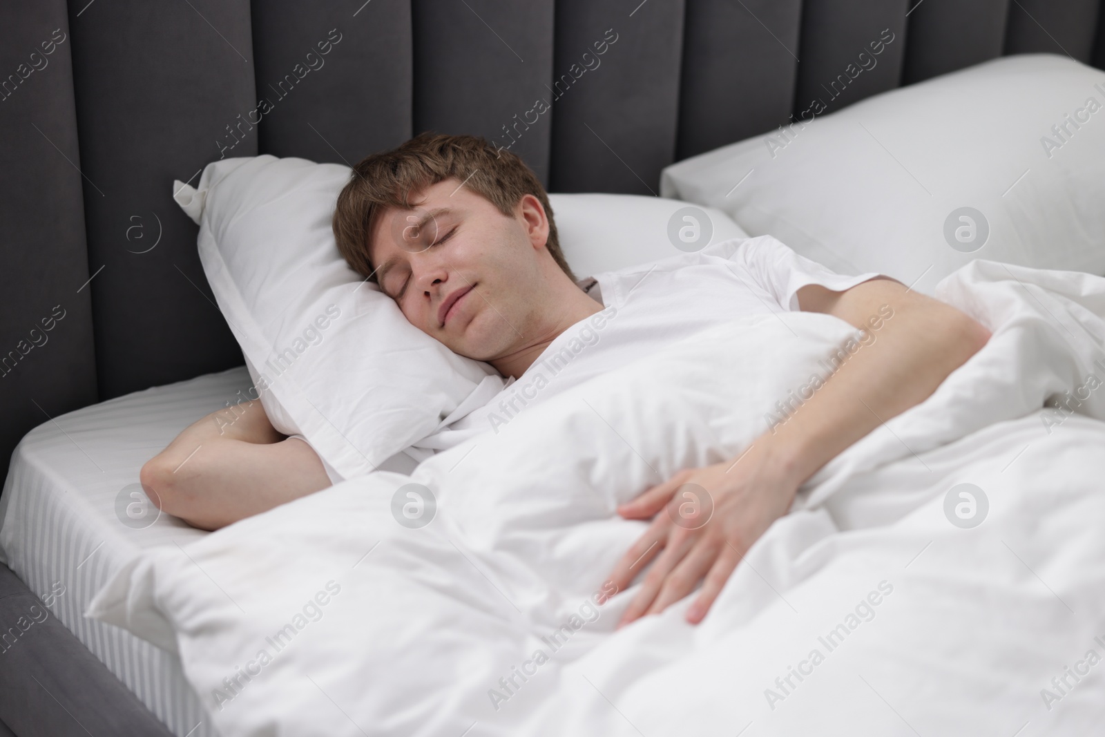 Young man sleeping in bed at home Photo of Young man sleeping in bed at home
