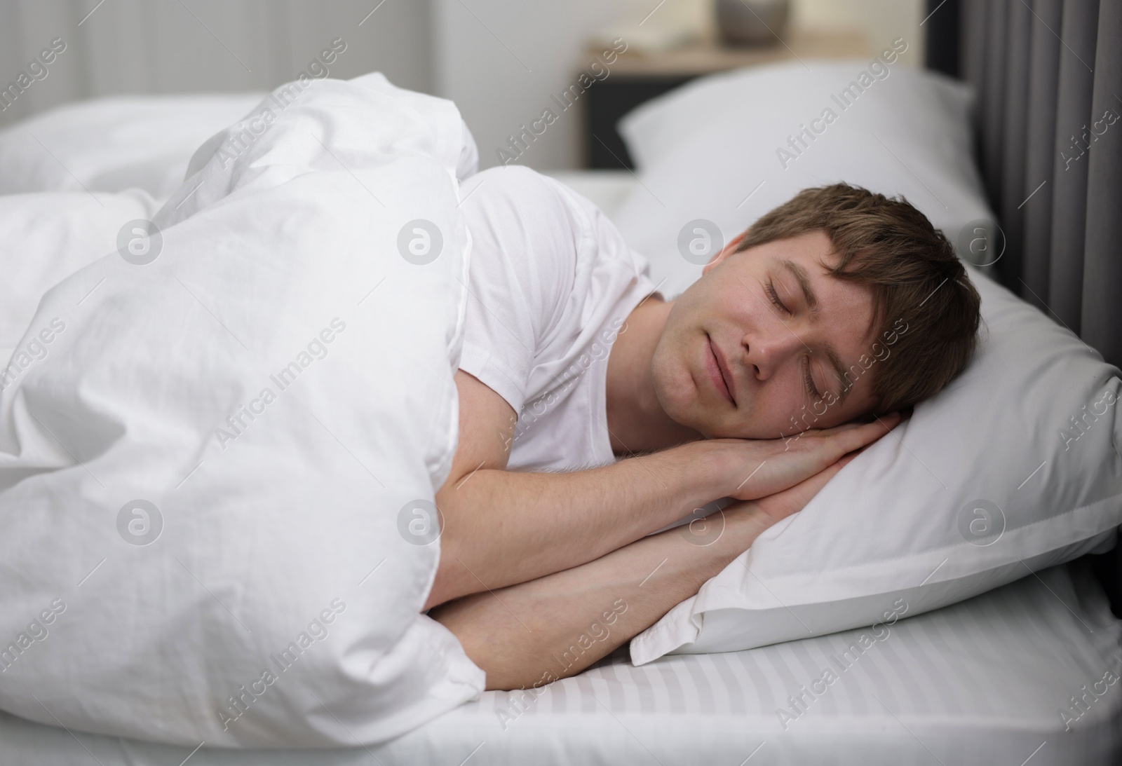 Young man sleeping in bed at home Photo of Young man sleeping in bed at home