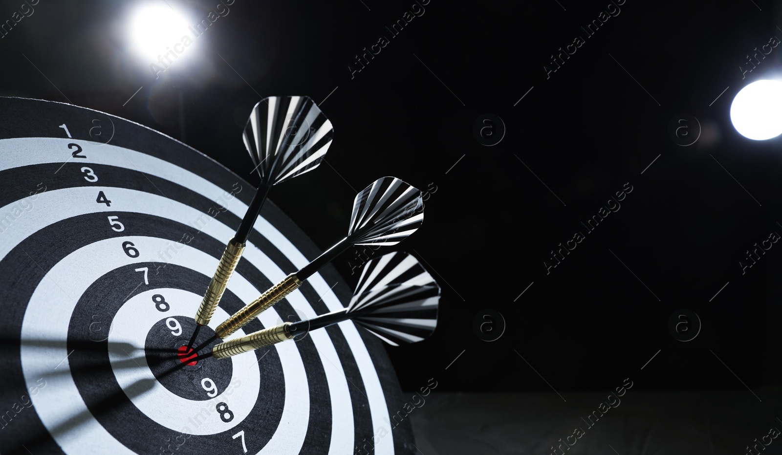 Targeting. Dart board with arrows on dark background, closeup. Space for text Photo of Targeting. Dart board with arrows on dark background, closeup. Space for text