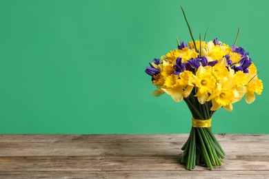 Photo of Bunch of beautiful flowers on wooden table against green background. Space for text