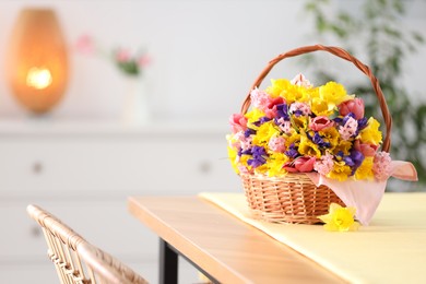 Photo of Wicker basket with beautiful flowers on wooden table indoors. Space for text
