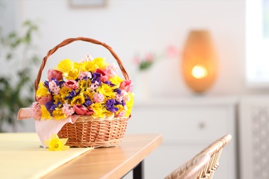 Photo of Wicker basket with beautiful flowers on wooden table indoors. Space for text