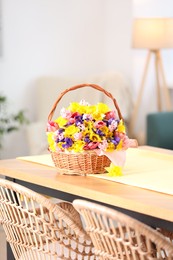 Photo of Wicker basket with beautiful flowers on table in dining room