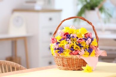 Photo of Wicker basket with beautiful flowers on table indoors. Space for text