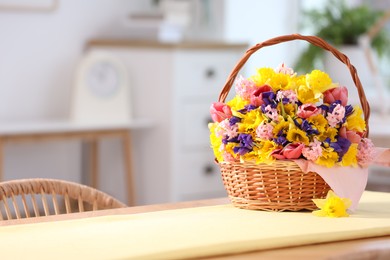 Photo of Wicker basket with beautiful flowers on table indoors. Space for text