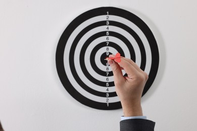 Photo of Targeting. Man with arrow aiming at dart board on light background, closeup