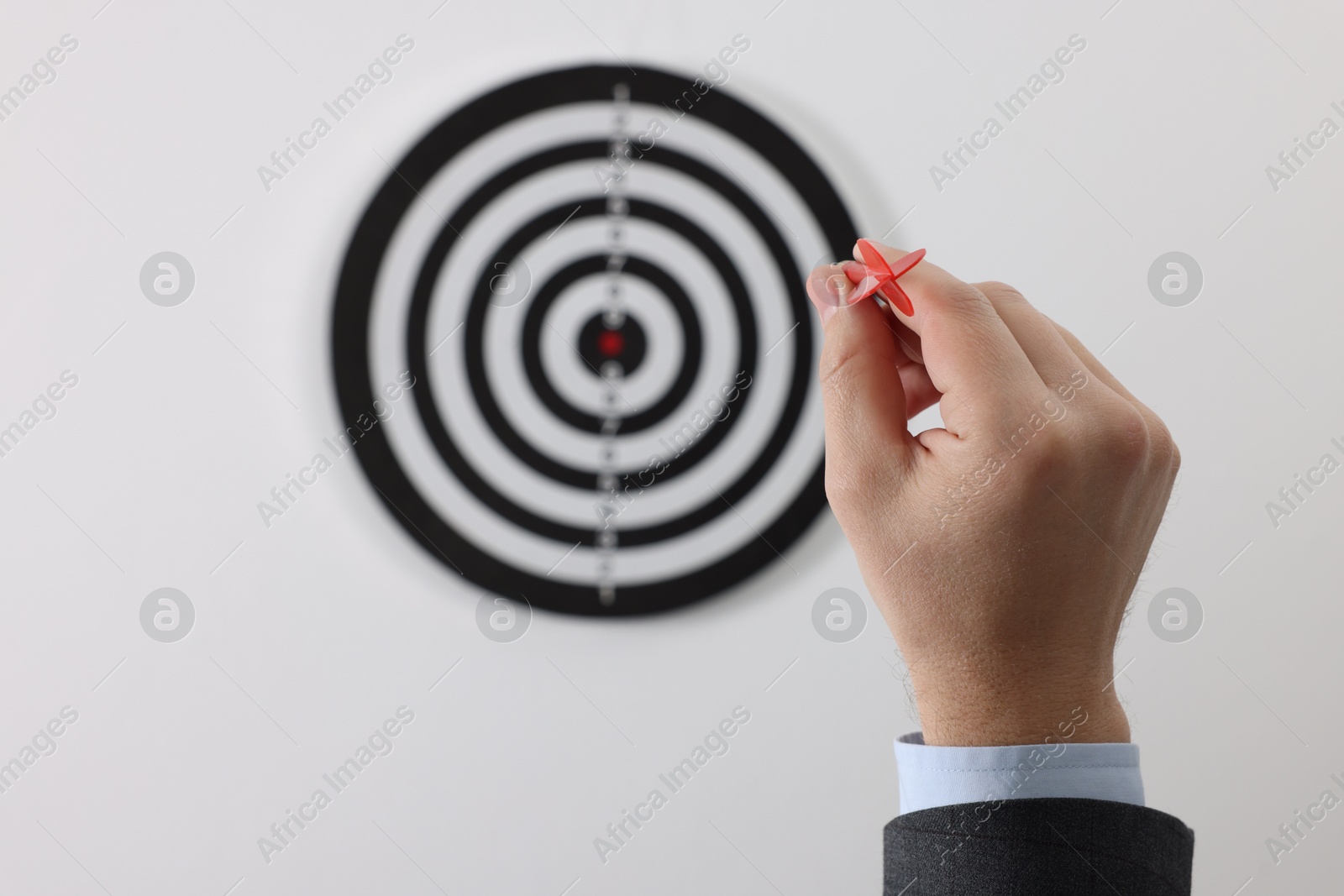 Targeting. Man with arrow aiming at dart board on light background, closeup Photo of Targeting. Man with arrow aiming at dart board on light background, closeup