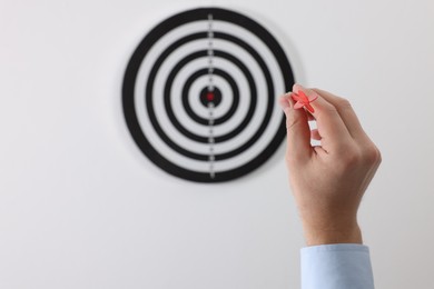 Photo of Targeting. Man with arrow aiming at dart board on light background, closeup