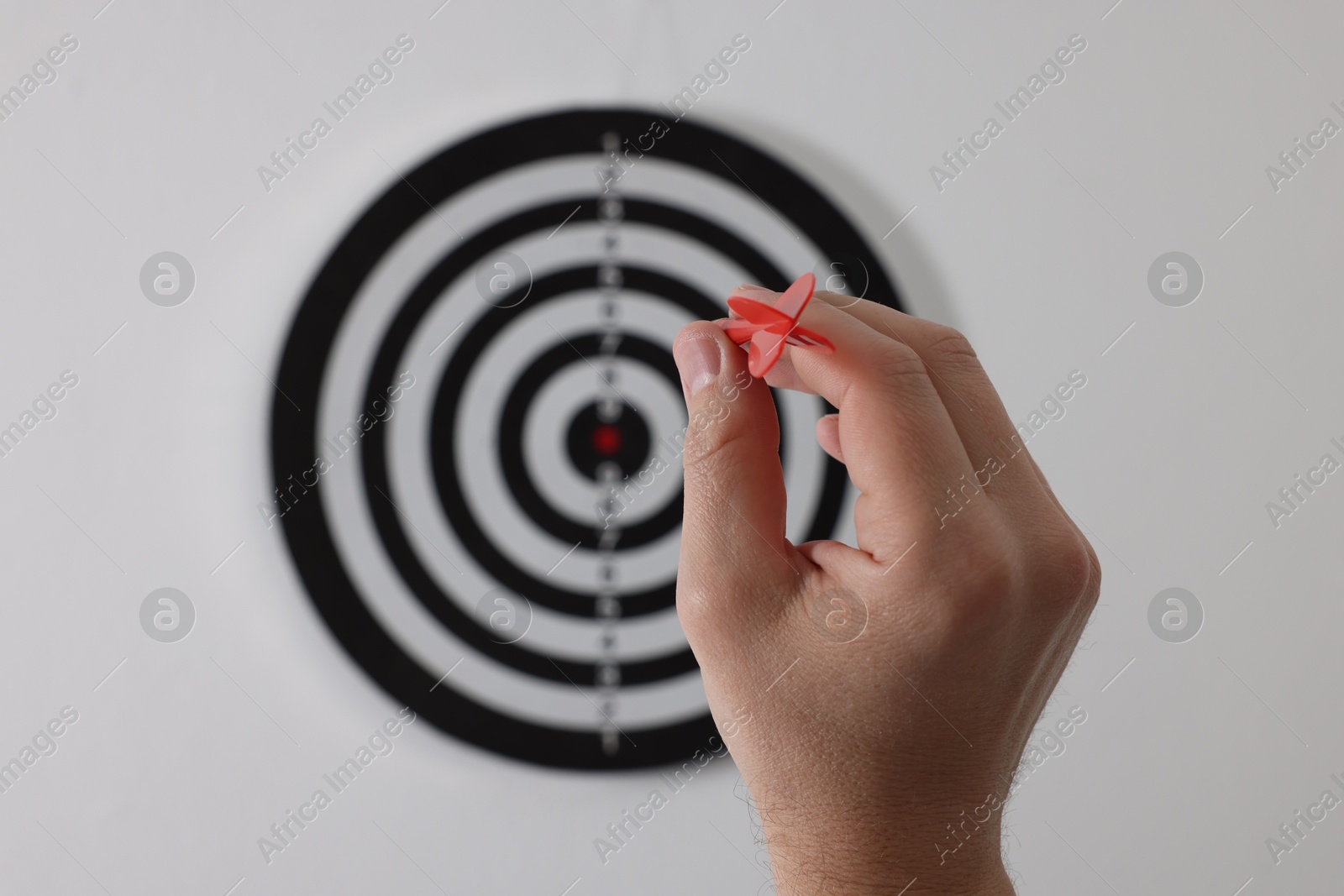Targeting. Man with arrow aiming at dart board on light background, closeup Photo of Targeting. Man with arrow aiming at dart board on light background, closeup