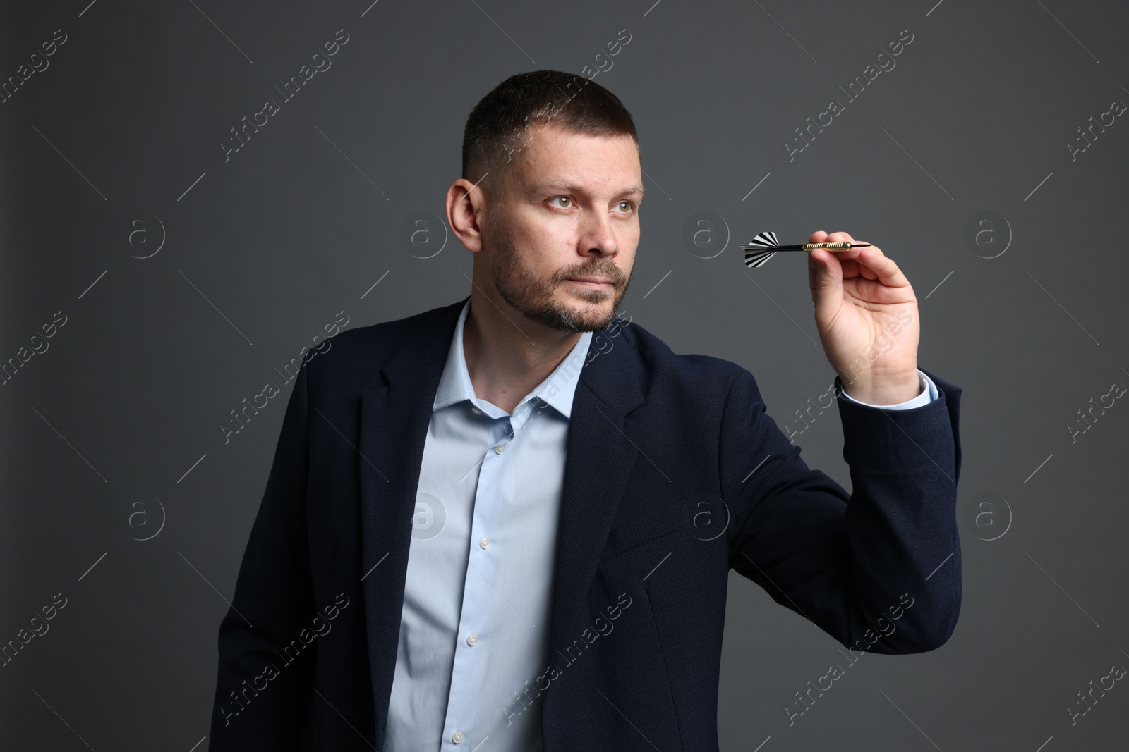 Targeting. Man with dart aiming on grey background Photo of Targeting. Man with dart aiming on grey background