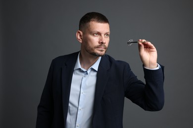 Photo of Targeting. Man with dart aiming on grey background